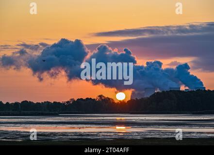 Peitz, Deutschland. Oktober 2023. Der Sonnenaufgang scheint hinter dampfenden Kühltürmen des Braunkohlekraftwerks Jänschwalde der Lausitz Energie Bergbau AG (LEAG). Die Braunkohle wird im nahe gelegenen Tagebau Jänschwalde abgebaut. Das Braunkohlekraftwerk soll bis Ende 2028 vom Netz genommen werden. Block A soll bereits 2025 abgeschaltet werden. Quelle: Patrick Pleul/dpa/Alamy Live News Stockfoto