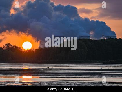 Peitz, Deutschland. Oktober 2023. Der Sonnenaufgang scheint hinter dampfenden Kühltürmen des Braunkohlekraftwerks Jänschwalde der Lausitz Energie Bergbau AG (LEAG). Die Braunkohle wird im nahe gelegenen Tagebau Jänschwalde abgebaut. Das Braunkohlekraftwerk soll bis Ende 2028 vom Netz genommen werden. Block A soll bereits 2025 abgeschaltet werden. Quelle: Patrick Pleul/dpa/Alamy Live News Stockfoto