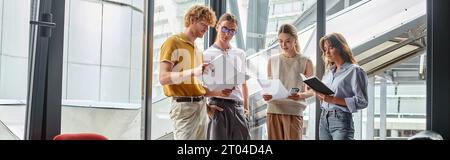 Vier Kollegen in Business Casual Outfits arbeiten an Dokumenten, Coworking-Konzepten, Banner Stockfoto