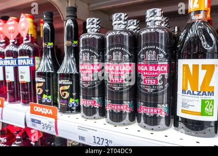 Samara, Russland - 1. Juli 2023: Schwarzer Rigaer Balsam mit Kirschgeschmack - traditioneller lettischer Kräuterlikör, fertig zum Verkauf im Regal in einem Supermarkt Stockfoto