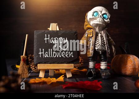 4. Oktober 2023: Herbst- und Halloween-Dekoration um eine Tafel mit Aufschrift: Happy Halloween. Skelett mit Hexenbesen gruselige KONZEPTFOTOMONTAGE *** Herbst und Halloween Dekoration um eine Kreidetafel mit Aufschrift: Happy Halloween. Skelett mit Hexenbesen Grusel Konzept FOTOMONTAGE Credit: Imago/Alamy Live News Stockfoto