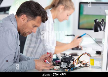 Leute, die einen Computer in einer Werkstatt reparieren Stockfoto