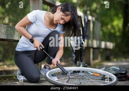 Eine junge Frau, die einen Fahrradreifen hochpumpt Stockfoto