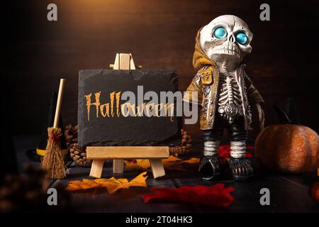 4. Oktober 2023: Herbst- und Halloween-Dekoration um eine Tafel mit Inschrift: Halloween. Skelett mit Hexenbesen gruselige KONZEPTFOTOMONTAGE *** Herbst und Halloween Dekoration um eine Kreidetafel mit Aufschrift: Halloween. Skelett mit Hexenbesen Grusel Konzept FOTOMONTAGE Stockfoto