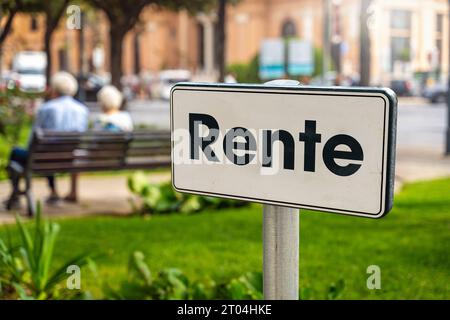 4. Oktober 2023: Ein pensioniertes Ehepaar sitzt in einem Park auf einer Parkbank mit einem Schild im Vordergrund mit der Aufschrift: Pension FOTOMONTAGE *** ein Rentner Pärchen sitzt in einem Park auf einer Parkbank mit einem Schild im Vordergrund mit Aufschrift: Rente FOTOMONTAGE Stockfoto