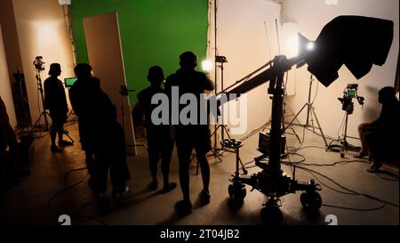 Silhouettenbilder von oder hinter den Kulissen der Videoproduktion, die im Filmstudio produziert wurden, einschließlich aller professionellen Licht- und Kameraausrüstung Stockfoto