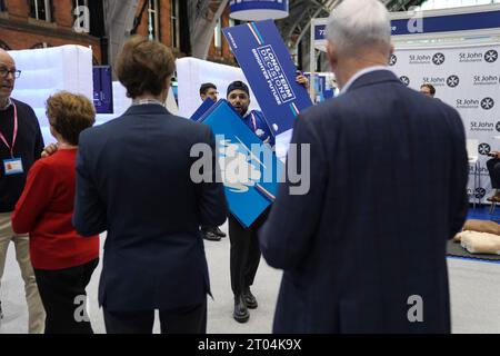 Parteimitglieder erhalten Plakate, während sie anstehen, um zu sehen, wie Premierminister Rishi Sunak während der Jahreskonferenz der Konservativen Partei im Manchester Central Convention Complex seine Hauptredner hält. Bilddatum: Mittwoch, 4. Oktober 2023. Stockfoto