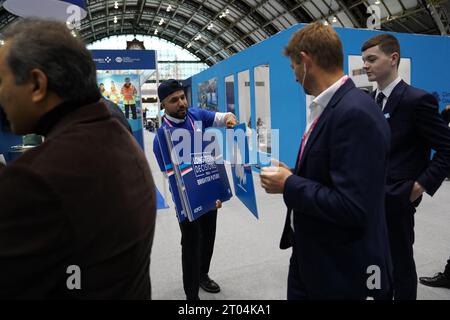 Parteimitglieder erhalten Plakate, während sie anstehen, um zu sehen, wie Premierminister Rishi Sunak während der Jahreskonferenz der Konservativen Partei im Manchester Central Convention Complex seine Hauptredner hält. Bilddatum: Mittwoch, 4. Oktober 2023. Stockfoto