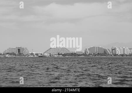 Bootsblick auf die Strandpromenade des Eilat Harbour, Luxushotels. (Von links nach rechts) Queen of Sheba, Royal Beach, Dan Eilat, Herods Palace in Schwarz-weiß Stockfoto