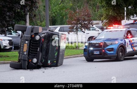 Der Unfallort in Mount Kisco Westchester, wo ein Polizist einen Jeep betreut, der auf seiner Seite umgekippt ist. Stockfoto