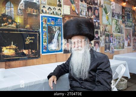 Ein jüdischer Mann mit einem Schtreimel-Pelzhut posiert für ein Foto in einer Sukkka auf Sukkot. In Monsey, Rockland County, New York. Stockfoto