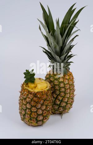 Frische Ananas, eine ganze Frucht und eine ausgehöhlte Frucht, gefüllt mit Fruchtbrei. Vor weißem Hintergrund einstellen Stockfoto