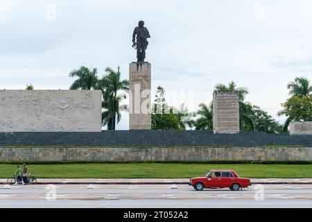 Skulpturenensemble und Gedenkstätte für Kommandeur Ernesto Che Guevara. Ein Lada Auto fährt von zwei Männern mit Fahrrädern vor dem Denkmal. Santa Clara, Cu Stockfoto