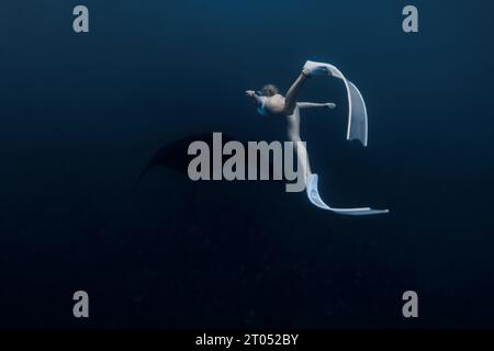 Frau schwimmt unter Wasser mit Mantarochen. Freitauchend mit Mantarochen auf dem tiefen Ozean Stockfoto