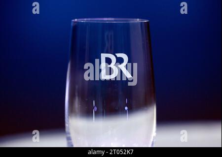 Das Logo des Bayerischen Rundfunks BR auf einem Glas vor dem TV-Duell der Sendung BR24 Wahl - die Konfrontation zur Landtagswahl 2023 im BR-Studio in Nürnberg. Der Bayerische Rundfunk ist die Landesrundfunkanstalt im Freistaat Bayern mit Sitz in München. Er ist Mitglied der Arbeitsgemeinschaft der öffentlich-rechtlichen Rundfunkanstalten der Bundesrepublik Deutschland ARD und hat die Rechtsform einer Anstalt des öffentlichen Rechts. Themenbild, Symbolbild Nürnberg, 03.10.2023 Bayern Deutschland *** das Logo des Bayerischen Rundfunks BR auf einem Glas vor dem TV-Duell der Sendung BR24 Elect Stockfoto