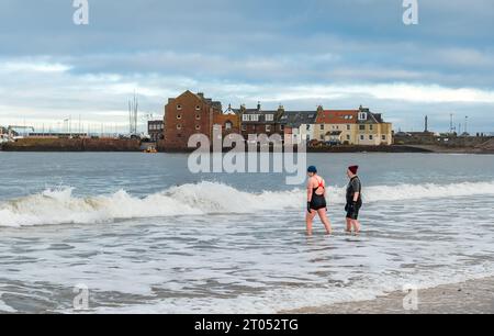 Zwei Frauen, die ins Wasser gehen, um in die Wildnis zu schwimmen, West Bay, North Berwick, East Lothian, Schottland, UK Stockfoto