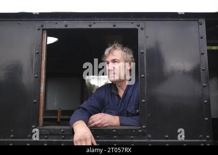 Cholsey & Wallingford Railway, Oxfordshire, britischer Zugführer, der sich aus dem Fenster seiner Dampflokomotive beugt, Restaurierung des Kulturerbes, Heritage Railway Stockfoto