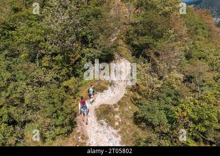 Aktives Paar, das auf dem Wanderweg durch den Wald spaziert, die Aussicht von einem Berggipfel genießt, Drohnenaufnahme. Stockfoto