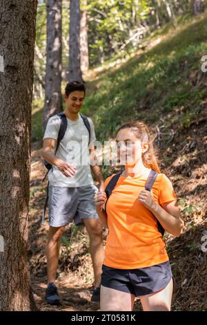 Ein junges Paar, eine Frau und ein Mann, die eine Sommerwanderung durch einen grünen Wald genießen. Reise-Lifestyle-Konzept. Stockfoto