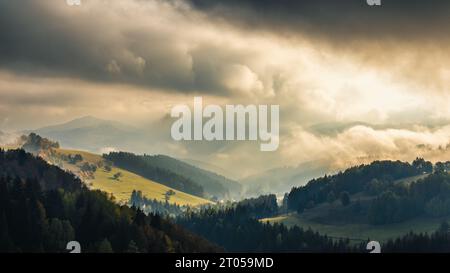 Herbstliche nebelige Berglandschaft mit Morgensonnenstrahlen, die durch die Wolken strahlen. Die Region Orava in der Slowakei, Europa. Stockfoto
