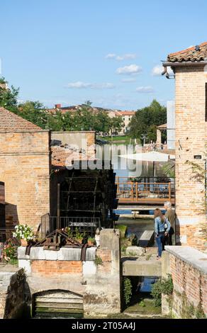 Ein junges Paar beobachtet die alte italienische Wassermühle in der kleinen Stadt Dolo am Ufer des Flusses Brenta Stockfoto