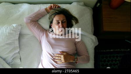 Die Frau legt sich ins Bett, um sich auszuruhen und ein Nickerchen zu machen Stockfoto