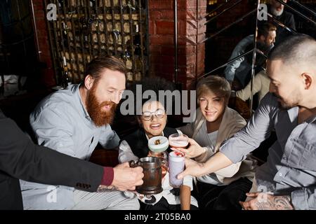 Fröhliche multiethnische Kollegen, die in der Cocktailbar mit alkoholischen Getränken tosten, Freizeit und Spaß Stockfoto