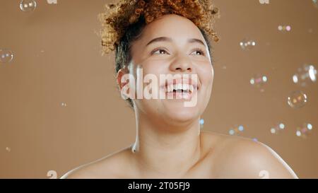 Glückliche Frau, Blasen und Haut für Schönheit, glücklich mit Naturkosmetik und Leuchten auf braunem Hintergrund. Dermatologie, Wellness mit Hautpflege und Flüssigkeit Stockfoto