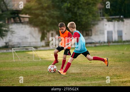 Zahlende Jungen tragen Sportuniform und spielen Fußball. Wettkampf zwischen Spielern, die Fußball laufen und treten. Kinderschulteam. Stockfoto