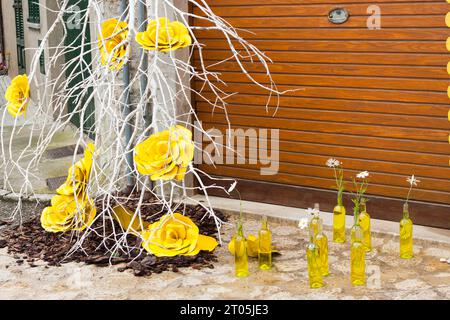 Zweig mit gelben Rosen und einigen gelben Flaschen mit Gänseblümchen auf dem Boden auf der Blumenmesse „Costitx en Flor“ (Costitx in Bloom), Mallorca, Spanien Stockfoto