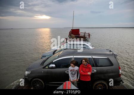 Touristen, Mutter und Sohn reisen mit einer kleinen hölzernen Fähre auf dem Brahmaputra River, transportieren Autos, Waren und Menschen zur Insel Majuli, Assam, Indien Stockfoto