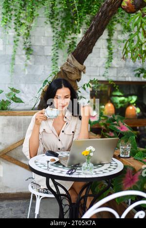 Junge ukrainische brünette Frau, die mit Laptop arbeitet und Kaffee im Café trinkt Stockfoto