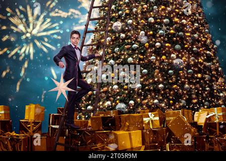 Wunderschöner Mann mit Geschenken in der Nähe des weihnachtsbaums Stockfoto