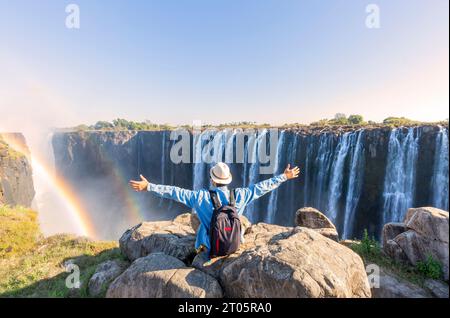 Mann, der auf einem Felsen sitzt und die Victoria Falls - Simbabwe genießt Stockfoto