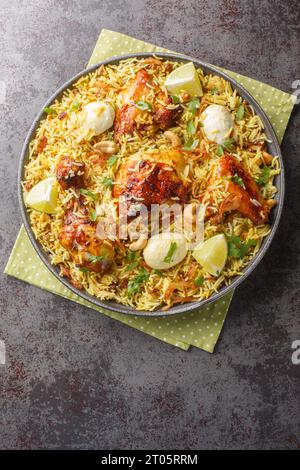 Scharfer Hühnchen-Biriyani-Reis mit in Scheiben geschnittenen Eiern auf dem Teller auf dem Tisch. Vertikale Draufsicht von oben Stockfoto