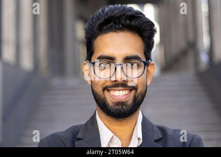 Nahaufnahme Porträt eines Geschäftsmannes, eines Mannes im Business-Anzug, der lächelt und in die Kamera blickt, eines erfolgreichen Investorenbankers vor dem Bürogebäude. Stockfoto