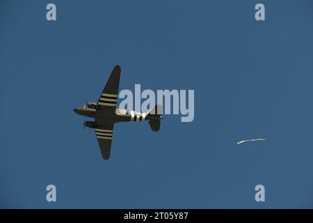 WWII RAF Dakota DC-3 C-47 im Flug gegen einen blauen klaren Himmel. Die Hintertür ist offen, und ein Windschutzband wurde aus dem Flugzeug fallen gelassen Stockfoto