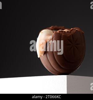 Cadbury's Creme Egg, das am Rand einer weißen Oberfläche auf grauem Hintergrund weht Stockfoto