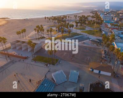 Luftaufnahmen mit einer Drohne während eines Winteruntergangs in Venice Beach, Los Angeles, Kalifornien, auf die Basketballfelder, Palmen und kurvige lan Stockfoto