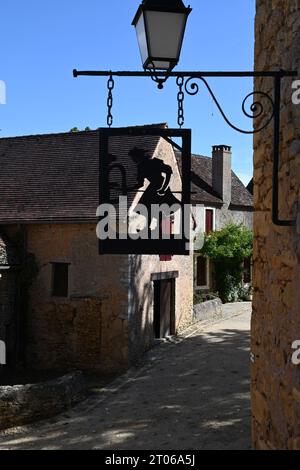 Ein Metallschild zeigt einen mittelalterlichen Bäcker, der seinen Brotbackofen in Urval, Dordogne, Frankreich, pflegt. Das Dorf hat einen Gemeinschaftsofen aus dem 15. Jahrhundert. Stockfoto