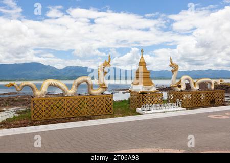 Wahrzeichen der Stadt Phayao in Nordthailand. Naga-Statue und goldene Stupa auf dem Phayao-See und im Hintergrund der Berge. Stockfoto