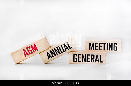 Die Hauptversammlung ist das Symbol der Jahreshauptversammlung. Konzeptwort AGM auf Holzwürfeln. Weißer Hintergrund.Kopierbereich. Stockfoto