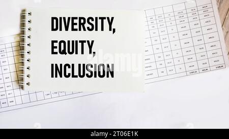 Das Wort Diversity, Equity and Inclusion auf einem Notizblock mit Papieren und Zahlen auf hölzernem Hintergrund. DEI-Konzept für Unternehmen. Kopierbereich Stockfoto