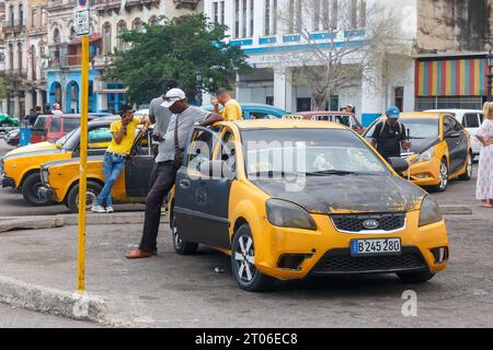 Eine Gruppe von gelben Taxis wartet auf Kunden in der Gegend von Parque Central. Ein Fahrer neigt sich zum Dach seines Fahrzeugs. Stockfoto