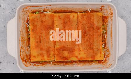 Lasagne zusammenbauen. Die letzte Lasagne mit Marinara-Sauce überziehen. Rezept für Spinat-Lasagne Stockfoto