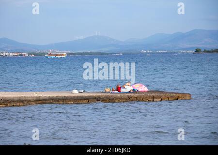 Vodice, Kroatien - 16. September 2023: Junger Mann, der allein auf dem Seebrück liegt und telefoniert Stockfoto