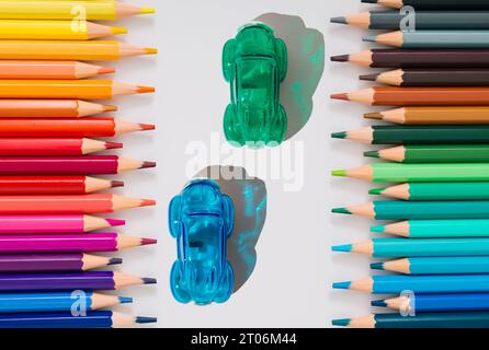 Kreatives Design für Rennwagen aus farbigen Bleistiften und Spitzstiften auf weißem Hintergrund. Minimales trendiges Back-to-School-Konzept. Stockfoto