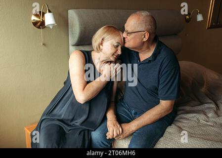 Glückliches älteres Paar. Eine ältere Frau streichelt die Hand ihres Mannes und drückt sanft gegen ihn. Stockfoto