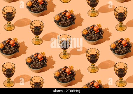 Kreatives Herbstmuster mit gefallenen Blättern, Beeren, Kürbissen, Tannenzapfen und Gläsern Rotwein auf pastellorangenem Hintergrund. Minimale Naturidee. Stockfoto