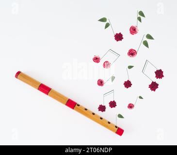 Kreatives Layout aus Holzflöte und Musiknoten aus verschiedenen Blumen auf weißem Hintergrund. Minimales trendiges Holzinstrument-Konzept. Stockfoto